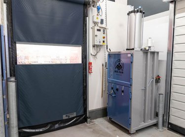 Presse à balles A305 bleue installée près d’une porte arrière