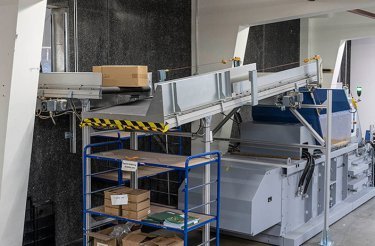 Convoyeur d’alimentation transportant des cartons vers une presse à balles automatisée