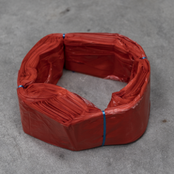 Cartouche de sacs en plastique rouges Infinity format standard, liée avec du fil bleu, disposée en anneau sur une surface grise
