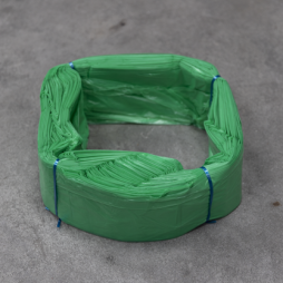 Cartouche de sacs en plastique verts Infinity format standard, liée avec du fil bleu, disposée en anneau sur une surface grise